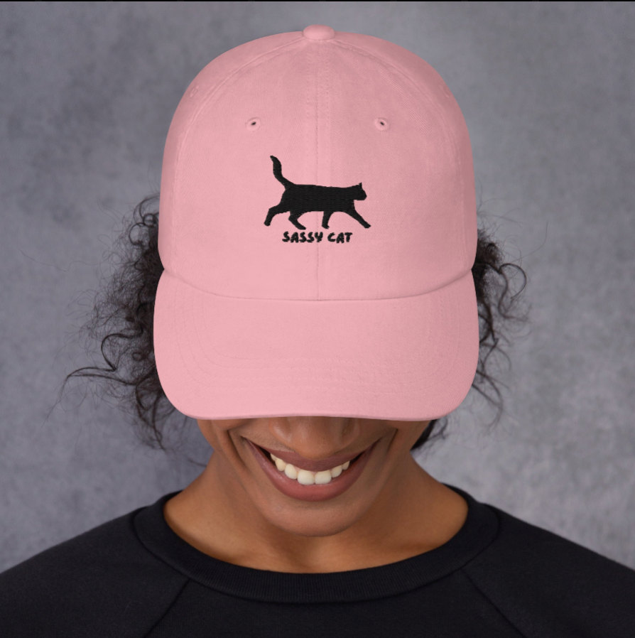 Person wearing a pink Sassy Cat embroidered dad hat featuring a playful black cat graphic. Perfect for casual outfits and cat lovers looking for a stylish accessory.